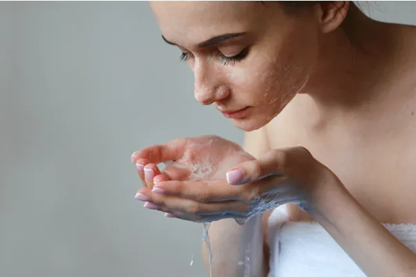 Kobieta oczyszcza skórę twarzy przy pomocy delikatnego, pieniącego się żelu myjącego